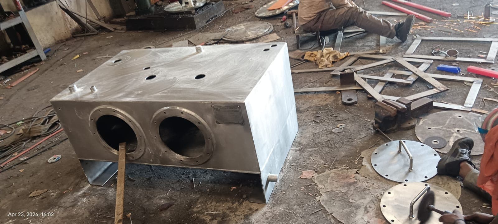 Fabricated metal housing with circular openings on a workshop floor