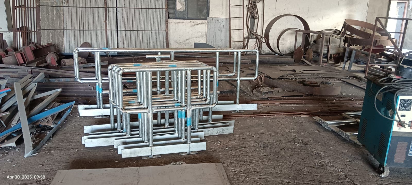 Prefabricated galvanised piping assemblies stacked in a workshop