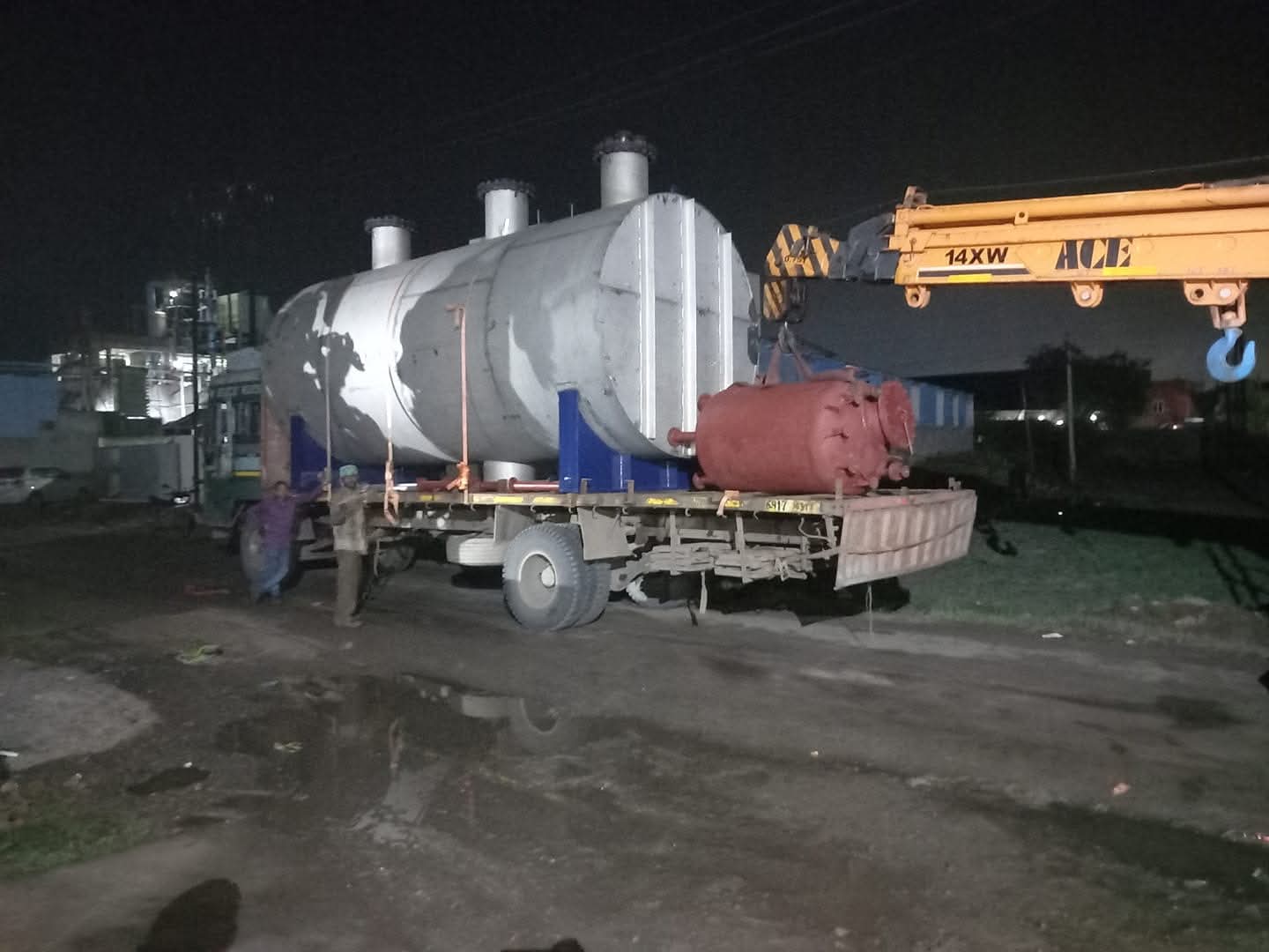 Process equipment loaded on a trailer beside a mobile crane