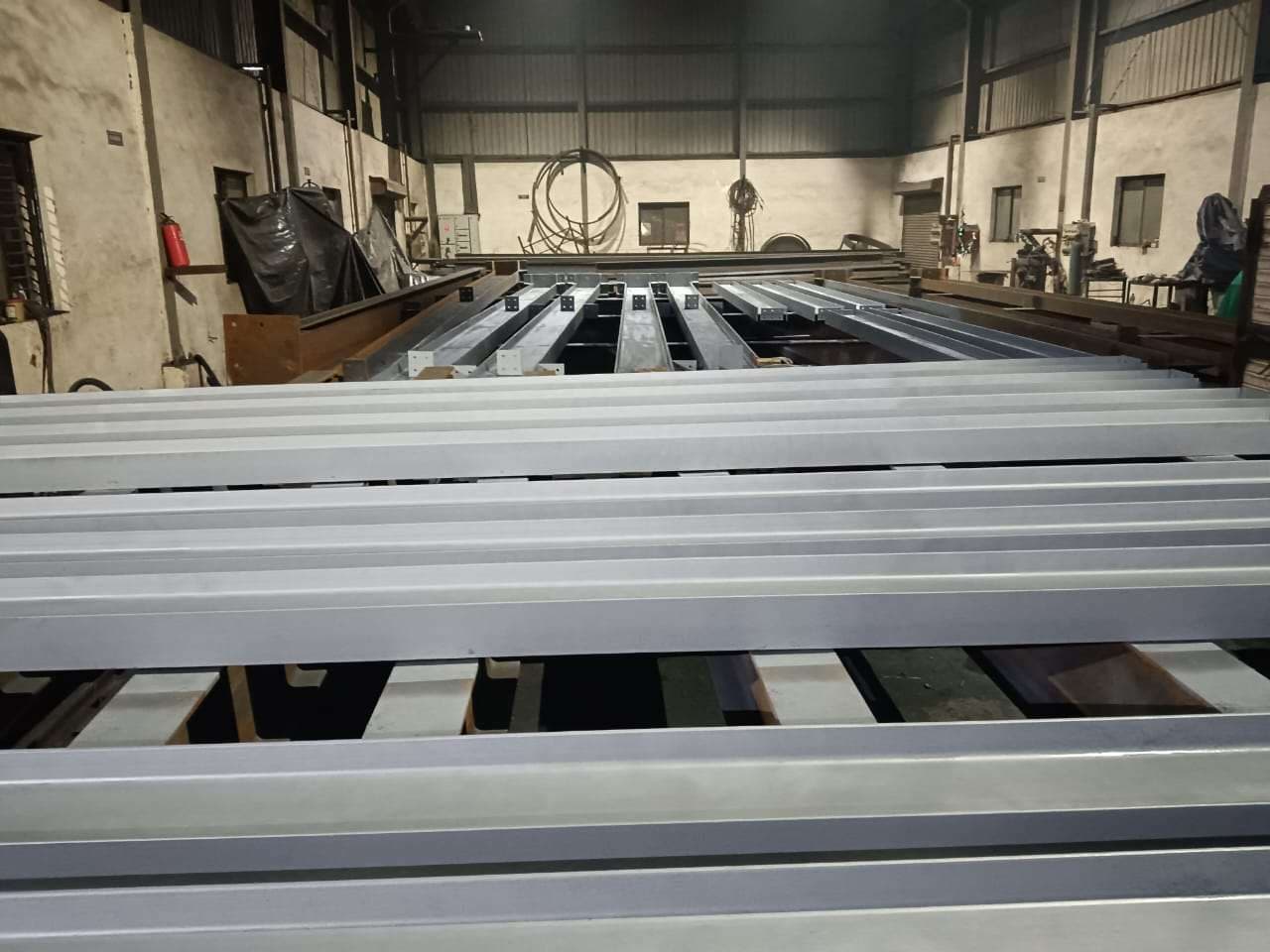 Painted structural steel members laid out in a fabrication workshop