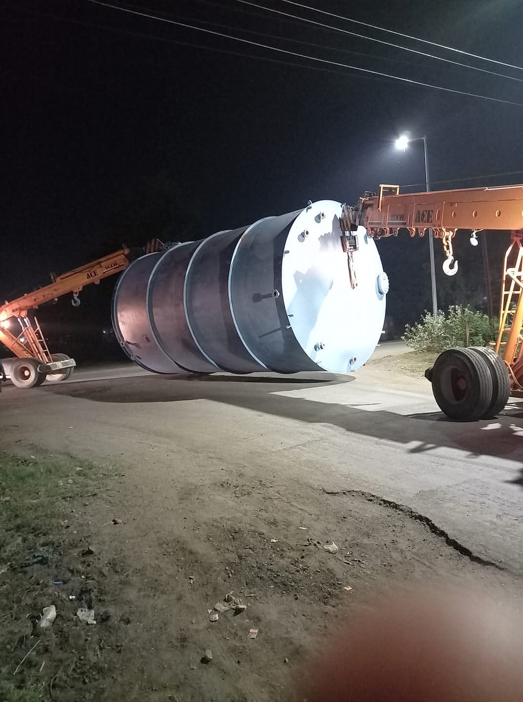 Process tank being lifted by mobile cranes at night